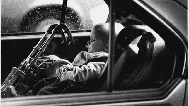 Una fotografía en blanco y negro de un bebé en un coche. 