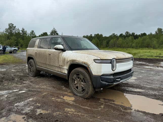 Front 3/4 view of a white Rivian R1S in the mud