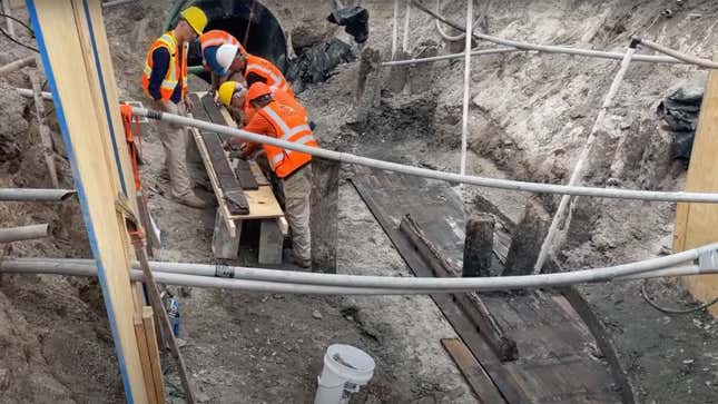 An image showing workers recovering parts of an ancient ship. 