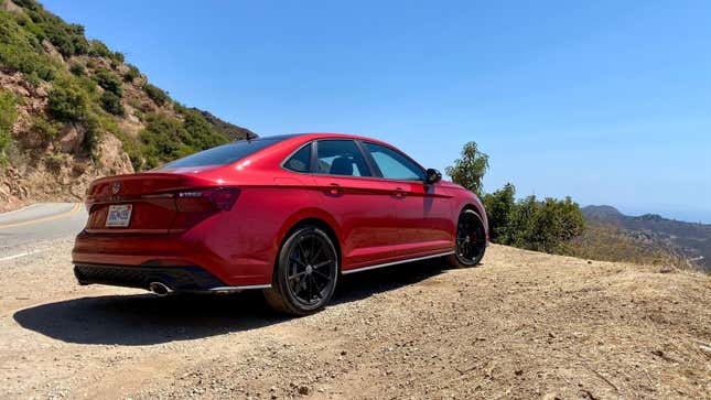 A rear 3/4 shot of the kings red GLI parked on dirt next to mountains