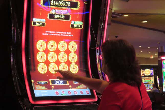 A gambler touches the screen of a slot machine at Harrah&#39;s casino in Atlantic City, N.J. on Sept. 29, 2023. Figures released on Tuesday, Feb. 20, 2024, by the American Gaming Association show that the U.S. commercial casino industry had its best year ever in 2023, winning $66.5 billion from gamblers. When figures from tribal casinos are tallied later this year, the combined total is expected to approach $110 billion for 2023. (AP Photo/Wayne Parry)