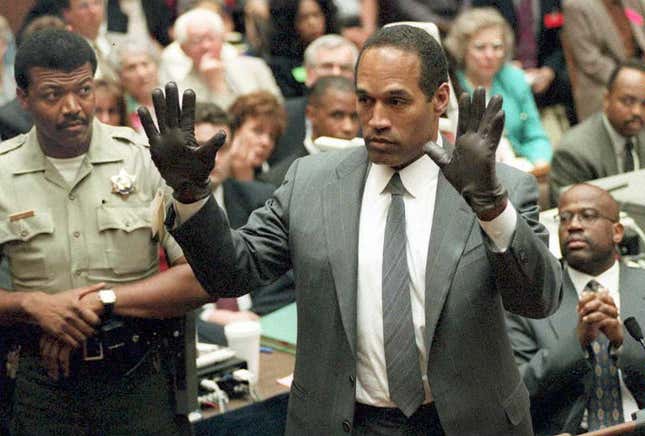 O.J. Simpson shows the jury a new pair of Aris extra-large gloves, similar to the gloves found at the Bundy and Rockingham crime scene 21 June during his double murder trial in Los Angeles. Depety Sheriff Roland Jex(L) and Prosector Christopher Darden(R) look on.