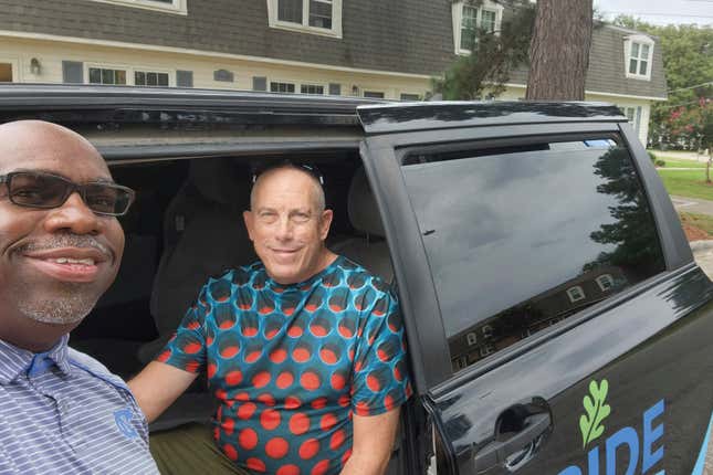 Driver Milton Barnes poses for a photo with customer David Bunn in front of his RIDE van in Wilson, N.C. on Aug. 24, 2023. The city of Wilson, North Carolina, ended its bus service in September 2020 to offer on-demand van trips anywhere in town for less than $3 a ride. Even during the pandemic, which sent public transit ridership plummeting, it surged 300% in Wilson. (Courtesy of Milton Barnes via AP)