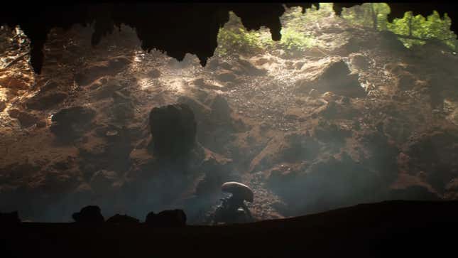 Un xénomorphe sortant de l’entrée d’une grotte, éclairé par le soleil.