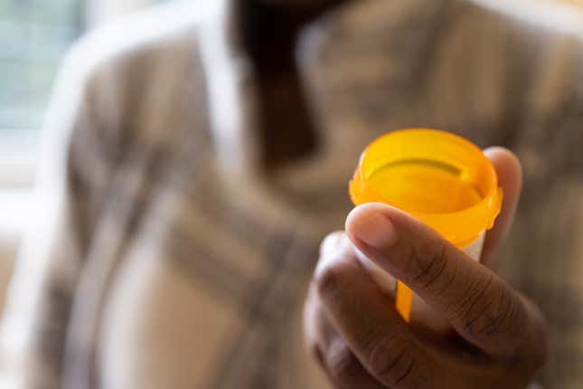 Woman holding open prescription pill bottle.