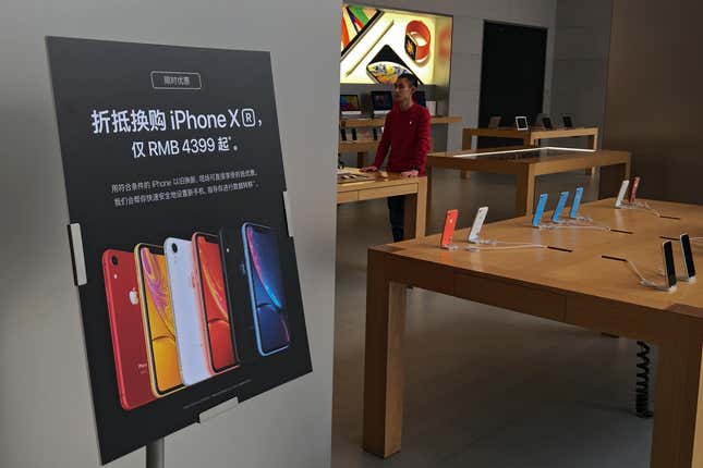 FILE - A trade-in for iPhone XR promotion board is displayed as an Apple employee waits for customers at its retail store in Beijing, Thursday, Jan. 3, 2019. Apple has agreed to pay $490 million to settle a class-action lawsuit alleging CEO Tim Cook misled investors about a steep downturn in the iPhone&#39;s sales in China that culminated in a jarring revision to the company&#39;s revenue forecast. The preliminary settlement was filed Friday, March 15, 2024, in Oakland, Calif., federal court. (AP Photo/Andy Wong, File)