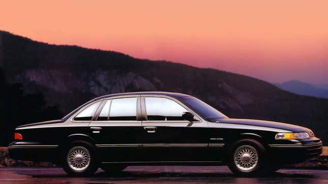 A photo of a black Ford Crown Vic sedan at sunset. 