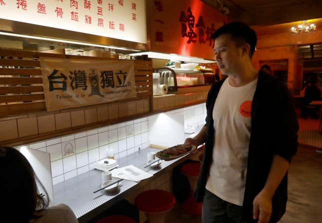 Restaurateur Andy Huang serves guests with a sign reading &quot;Taiwan is An Independent Country &quot; at his restaurant in Taipei, Taiwan, on May 7, 2023. Huang said he&#39;s become desensitized to military threats from China. Taiwan’s government is racing to counter China’s military, but many on the island say they don’t share the sense of threat. (AP Photo/Chiang Ying-ying)