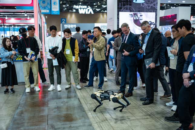 people stand around a four-legged dog-shaped robot