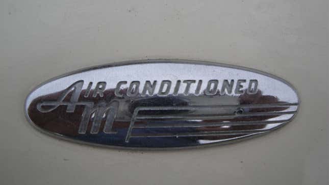 A photo of a chrome Air Conditioning badge on a car. 