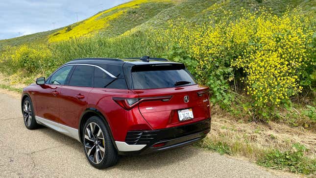 A rear 3/4 shot of the red ZDX in front of the grassy hills and yellow wildflowers