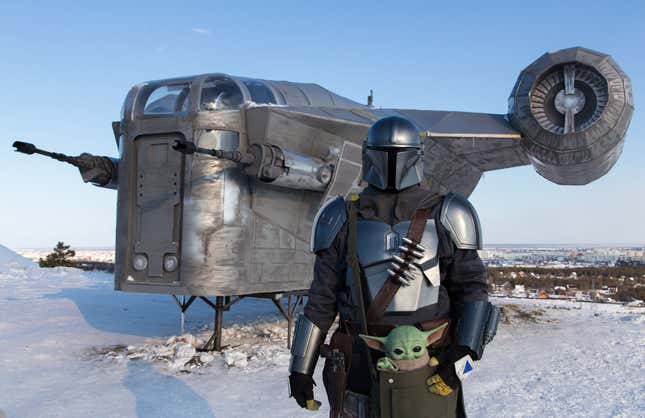 A man wearing a costume of the StarWars protagonist Din Djarin poses in front of a giant replica of the Razor Crest, a gunship from the StarWars spinoff series “The Mandalorian” used by the hit TV show’s mysterious bounty hunter to roam the galaxy’s outer reaches, in a park of the eastern Siberian city of Yakutsk on March 14, 2021.