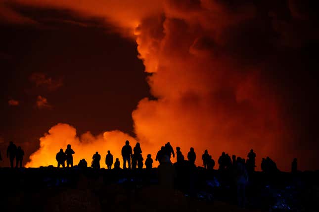 Spectators are silhouetted by an eruption (in background).