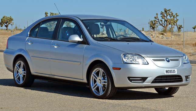 A silver Coda EV parked in front of some Joshua Trees