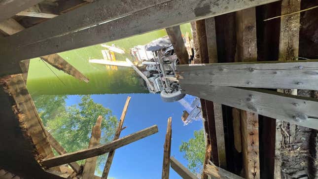 A photo of a truck crashed through the deck of a bridge. 