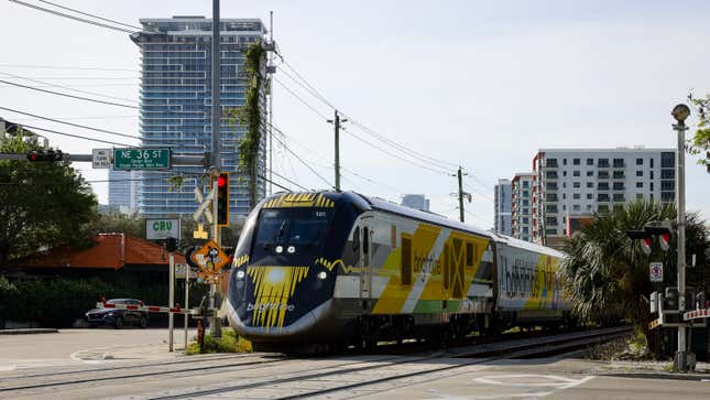 A photo of a Brightline train going through a level crossing. 