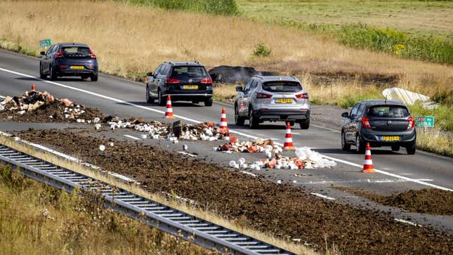 Cars drive past manure and debris dumped on the A50 road during a farmers’ demonstration against the government’s nitrogen policy, near Apeldoorn on July 27, 2022. - Netherlands OUT 