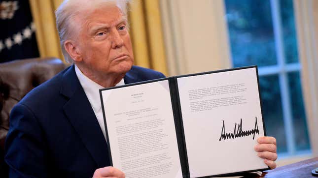 Donald Trump hold up a memorandum he signed ordering an immediate assessment of aviation safety and ordering an elevation of what he called “competence” over “D.E.I.” in the Oval Office at the White House.