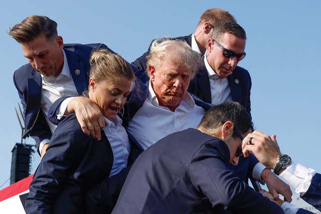 Trump is helped off stage after an assassination attempt. 