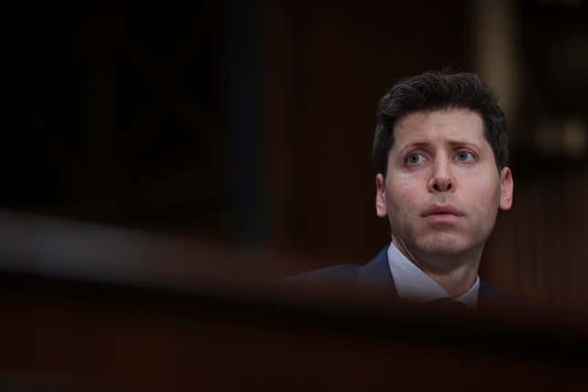 Sam Altman's head can be seen in a photo blurring and darkening his surroundings, he is looking to the right with a straight face