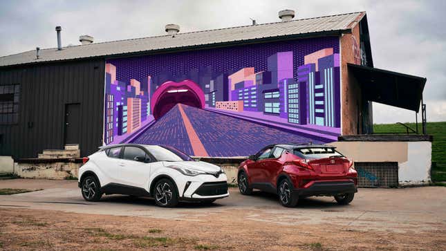 A photo of two Toyota C-HR crossovers parked by a warehouse. 