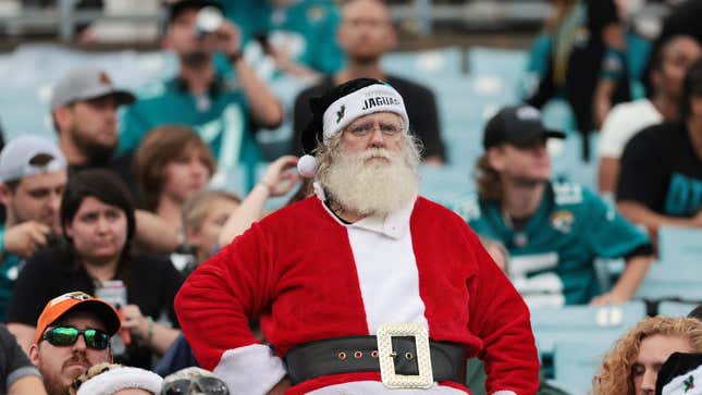 A man dressed as Santa at a Jacksonville Jaguars football game with fans in t-shirts in the background.