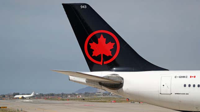 A photo of the tail of an Air Canada plane in an airport. 