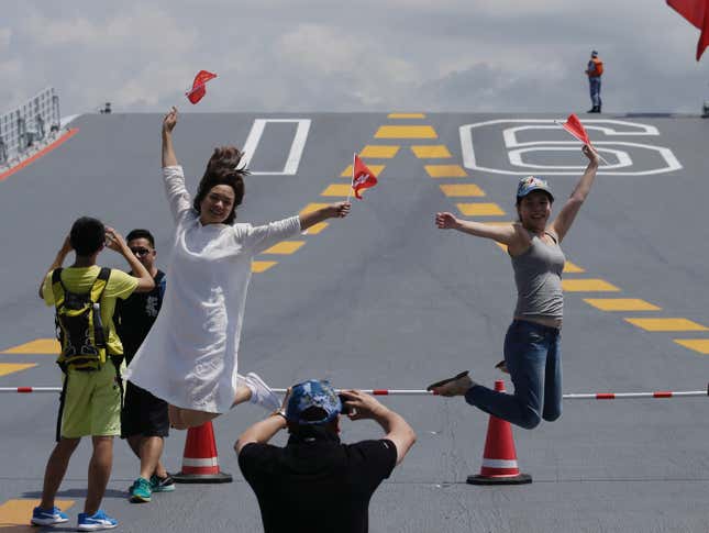 Visitors holding China and Hong Kong's flags pose for pictures on China's first aircraft carrier Liaoning during an open day at a naval base in Hong Kong, China, July 9, 2017. Picture taken July 9, 2017.