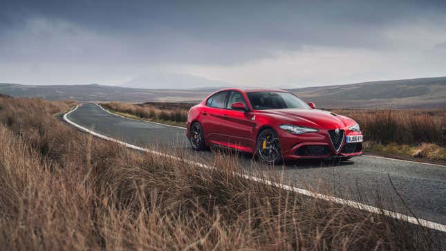 A photo of a red Alfa Romeo Giulia Quadrifoglio sedan on a country road. 