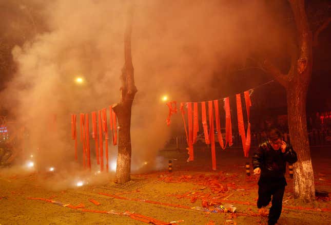 A man runs after lighting firecrackers to celebrate the start of the Chinese New Year in Beijing.