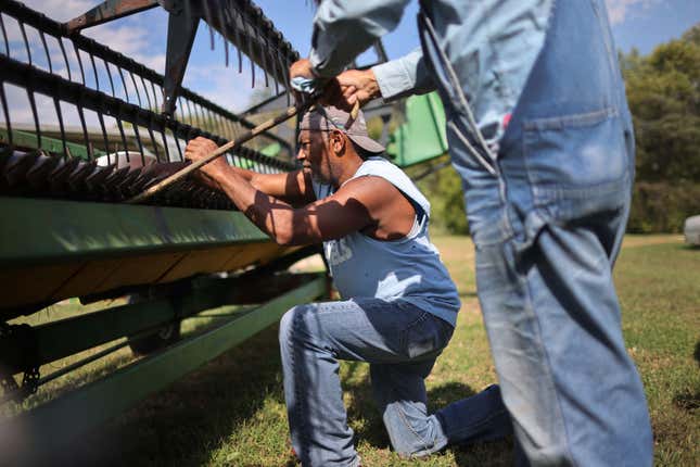 Norman Greer, 84, and William Ballard (L) repair a grain table on Greer’s farm as the threat of rain delays their plans to harvest soybeans on October 11, 2021, in Princeton, Indiana.