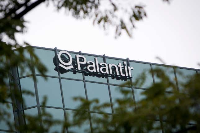 close up of Palantir logo on glass building, blurry branches in the foreground