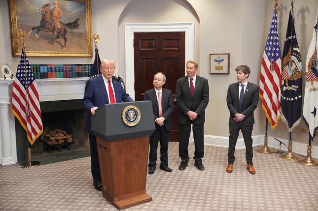 Donald Trump speaking at a podium with the presidential seal on it, Masayoshi, Larry, and Sam all have suits on and are standing in a row looking to their right and watching Trump