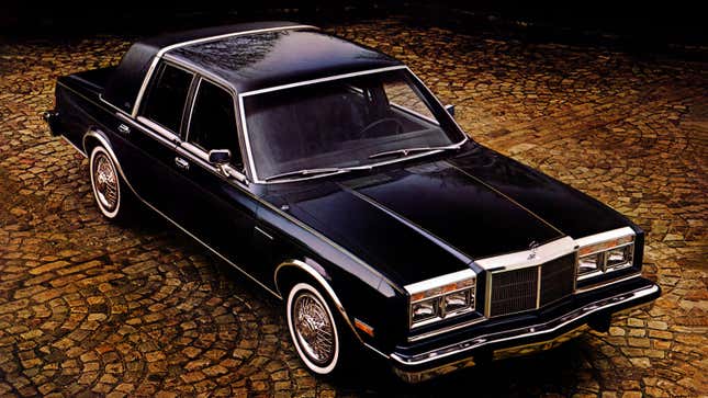 A photo of a black Chrysler New Yorker sedan on a cobble street. 