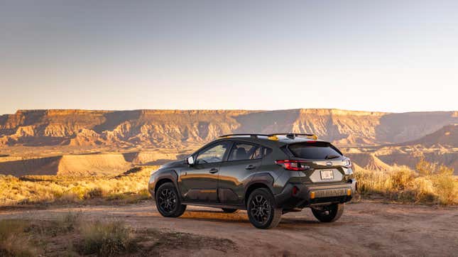 a dark green subaru crosstrek wilderness parked on dirt in front of a view of a giant canyon