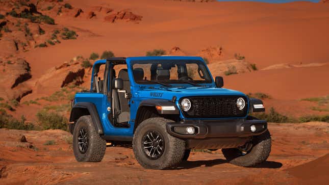 A blue two door wrangler parked on dirt with its roof and doors off