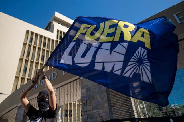 A woman waves a flag that reads in Spanish “LUMA Out” during a protest in front of the headquarters of LUMA Energy, the company that took over the transmission and distribution of the island’s electric authority. 