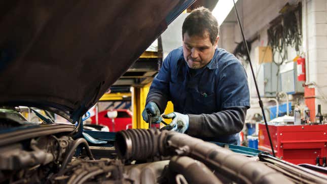 An mechanic working in the engine bay of a car