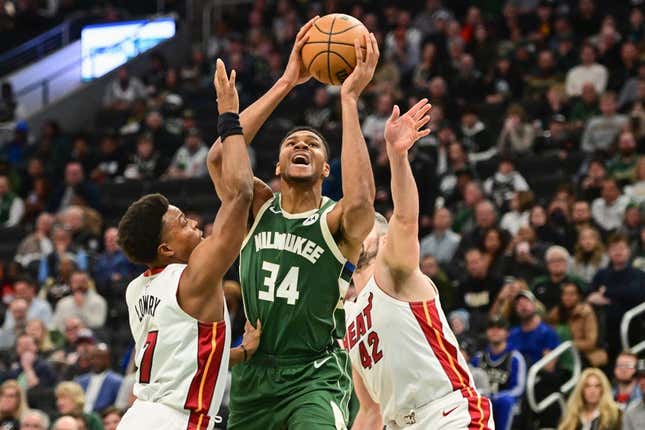 Oct 30, 2023; Milwaukee, Wisconsin, USA;  Milwaukee Bucks forward Giannis Antetokounmpo (34) takes a shot between Miami Heat guard Kyle Lowry (7) and forward Kevin Love (42) in the first quarter at Fiserv Forum.