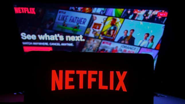 A Netflix logo is displayed on a phone in front of a TV.