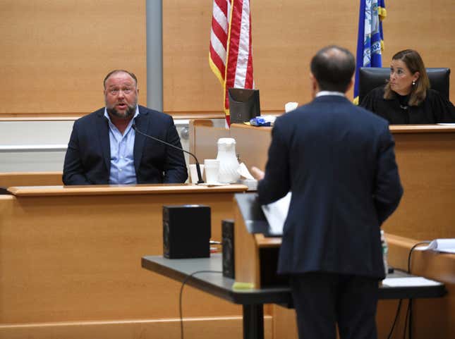 FILE - Infowars founder Alex Jones, left, is questioned by plaintiff&#39;s attorney Chris Mattei beside Judge Barbara Bellis, right, during testimony at the Sandy Hook defamation damages trial at Connecticut Superior Court in Waterbury, Conn. Thursday, Sept. 22, 2022. A $1.4 billion judgment was imposed against Jones for repeatedly calling the 2012 Newtown school shooting a hoax. (Tyler Sizemore/Hearst Connecticut Media via AP, Pool, File)