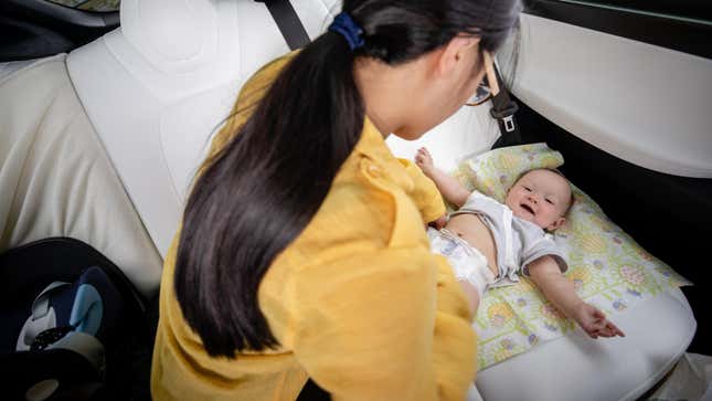 A mother changes her baby's diaper in the back of a Volvo