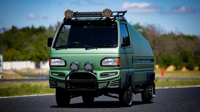 A photo of a green Kei truck with a camping pod on the rear. 