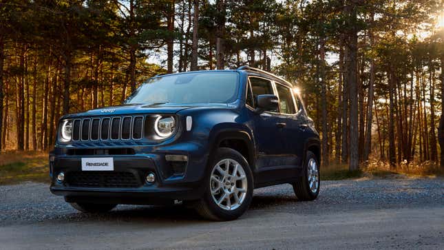 a dark blue jeep renegade parked on dirt in front of trees