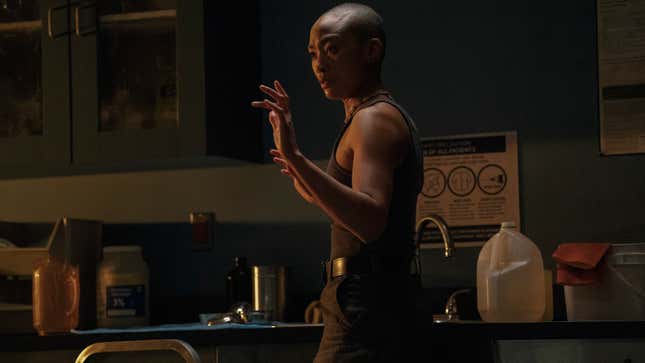 Nora raises her hands and looks at something off-screen.