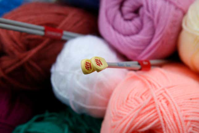 A stack of colorful balls of yarn with knitting needles stuck into the pile.