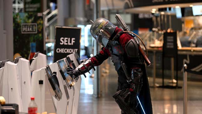 A cosplayer dressed as Boba Fett uses a self checkout machine during New York Comic Con 2022.