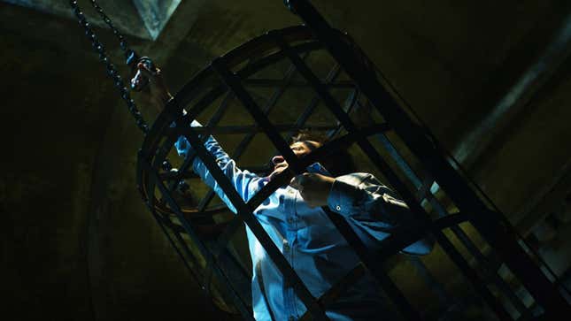 A person in a cage reaches for a handle. 