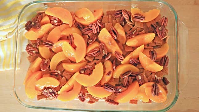Peaches, cereal, and pecans in a casserole dish.