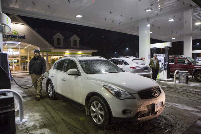 Jim Soroka, left, fills up his car at a busy gas station the evening before the arrival of Winter Storm Juno in Storrs, Connecticut on Monday, 26 January 2015.